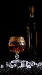 Glass with cognac and ice on a dark background. the concept of alcoholism and drinking
