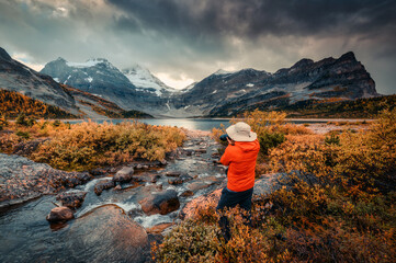 Fototapeta na wymiar Travel photographer man taking a photo with camera at mount assiniboine in autumn wilderness by lake magog on moody day