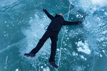 Fototapeta na wymiar Asian male tourist lying and enjoying on frozen lake with natural bubble