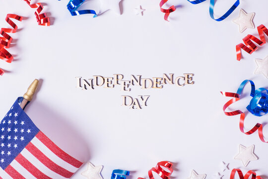 Independence day text. USA flags and Red and blue spirals and white stars top view, flat lay on white background.