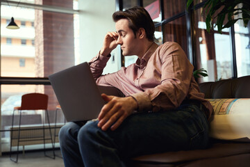 Exhausted young architect experiencing ocular fatigue from laptop use