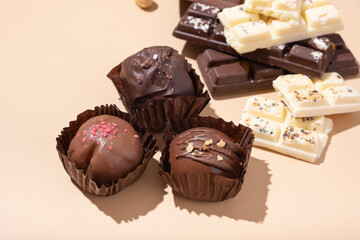 Craft white, milk and black chocolate candies on beige background flat lay, top view
