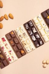 Craft white, milk and black chocolate candies on beige background flat lay, top view