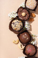 Chocolate craft nuts candies on white plate on beige background flat lay, top view