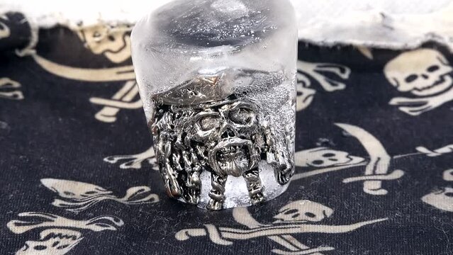 A pirate skull ring in a hat is defrosted from ice in a time lapse video