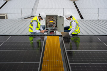 Engineer checks the operation of the solar cell system installed on the factory roof, engineers, technicians use computer to check the operation of solar cell panel installed on the industrial roof.