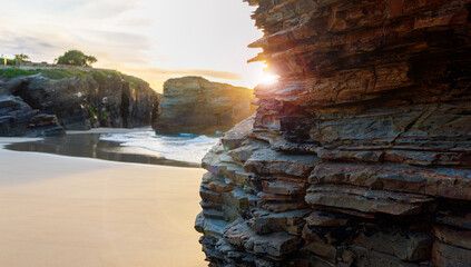 rock formation and sunlight on the beach at sunset