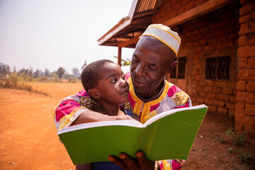 A grandfather reads fairy tales with his grandson in Africa, a moment of affection between grandfather and grandson