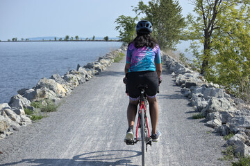 woman riding bike on gravel trail (young south asian, indian rider on bicycle trail) burlington...