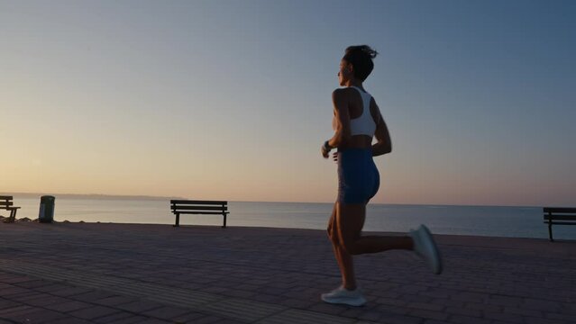 Running, caucasian woman and fitness on sunrise, blue sky for exercise goals, energy and power. Happy athlete, cardio and outdoor workout with motivation, smile and wellness.