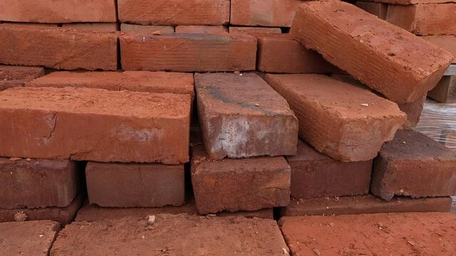 Stack of red clay bricks on the palette at warehouse close up