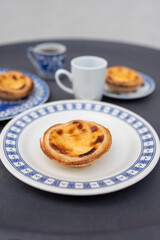 Portugal's traditional sweet dessert Pastel de nata egg custard tart pastry,  with coffee on a table in a street cafe