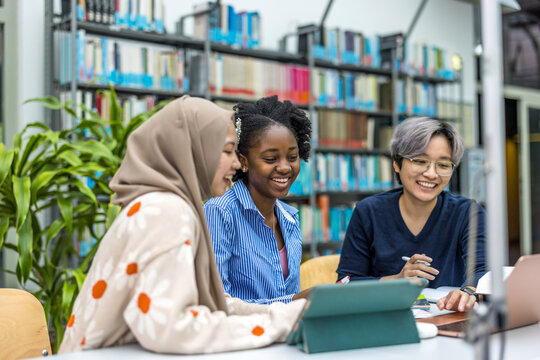 Multiethnic group of students sitting in a library and studying together
