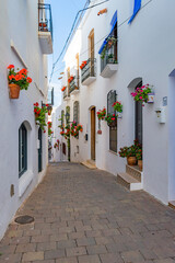 Fototapeta premium Narrow white village street with ornamental pots on the walls