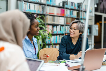 Multiethnic group of students sitting in a library and studying together
