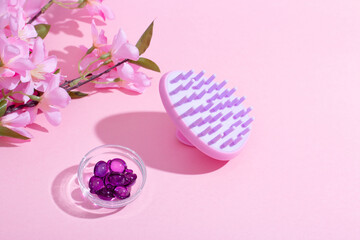 Scalp Massage and Cleansing Shampoo Brush with hair vitamins on pink background