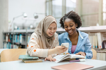 Female students using smartphone while sitting in a library
