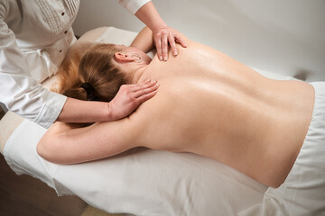Fototapeta na wymiar Masseuse female makes manual massage to blonde woman