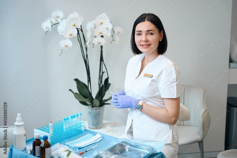 Wall mural happy doctor sitting in front of desk with medical stuff