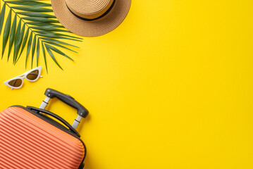 Summer trip concept. Above view photo of orange suitcase with straw hat, palm leaves and sunglasses near on isolated bright yellow background with copyspace
