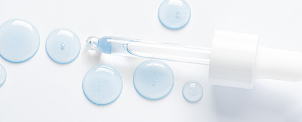 Drops of cosmetic serum and a pipette. A skin care product. White background.