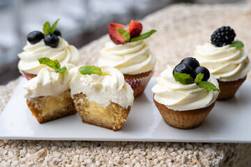 Cupcakes with different fruits on a white plate close-up.