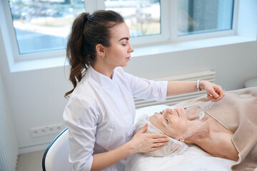 Beautician performing beauty neck procedure for adult lady