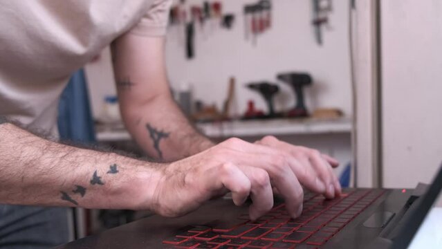 man hands typing on computer in carpentry workshop
