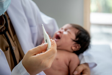Doctor holding a temperature measuring device, for measuring the fever of a baby newborn girl, 1-month-old. to health care and baby newborn concept.