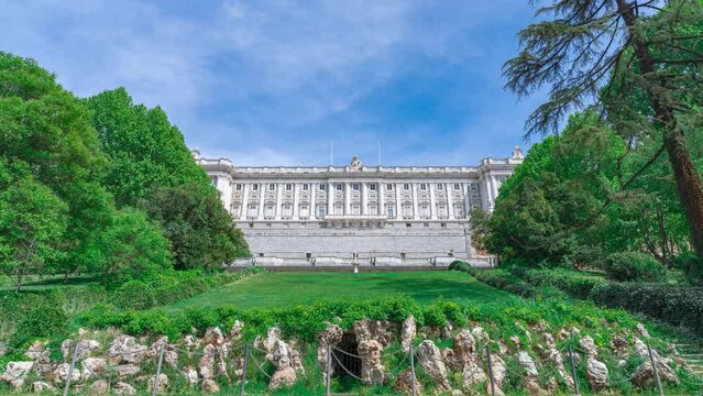 Palacio Real de Madrid visto desde los jardines con el tiempo acelerado y las nubes y los arboles en movimiento por el viento.