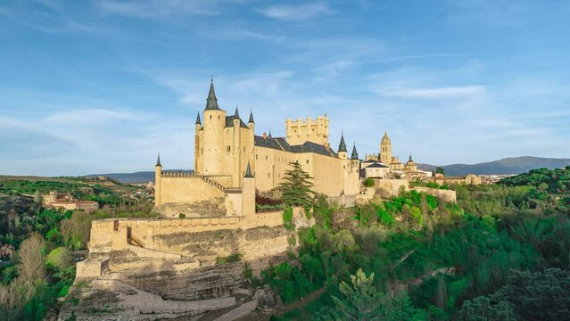 Medieval European fairytale castle, of princes and princesses, on top of a hill surrounded by vegetation, with the clouds moving by accelerated images, from Segovia, Castilla y Leon, Spain.