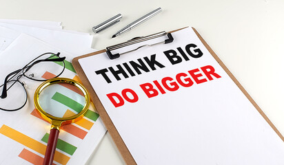 THINK BIG DO BIGGER text on clipboard with chart on white background, business concept