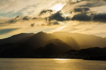 Mountains by the sea at sunset and the city on the shore.