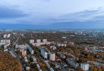 Fototapeta premium Aerial autumn evening city view. Residential district with park and dark blue cloudy sky. Kharkiv, Ukraine