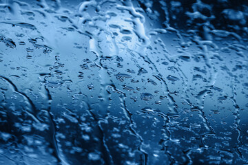 Abstract blue color background with water drops on glass surface with selective focus. Wet glass background with water drops texture. Soft focus
