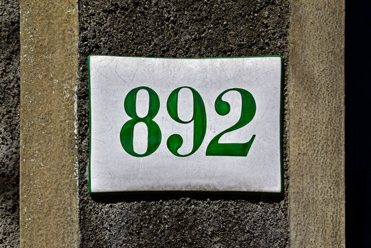 Street sign number 892 on a gray and yellow wall