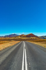 Fototapeta na wymiar Cover page with a paved road and Icelandic colorful and wild landscape with fjords and sea at summer time, West Iceland
