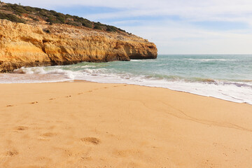 Fototapeta na wymiar Sandy beach next to a cliff and the ocean on a sunny winter day on the Seven Hanging Valleys Trail in southern Portugal.