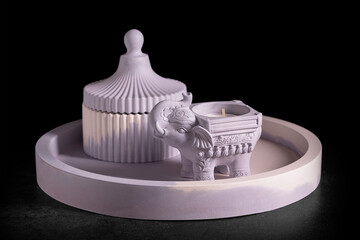 Gypsum products for home decoration. Elephant-shaped candlestick and jewelry box on a tray on a...