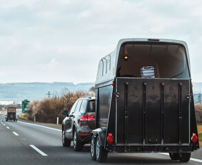 Car with a horse trailer on the road in Europe. Horse transport on the motorway.