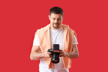 Male photographer with professional camera on red background