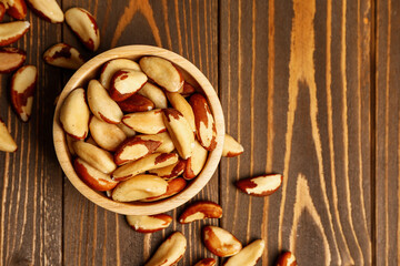 Bowl of tasty Brazil nuts on wooden background