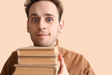 Young man reading book on beige background, closeup