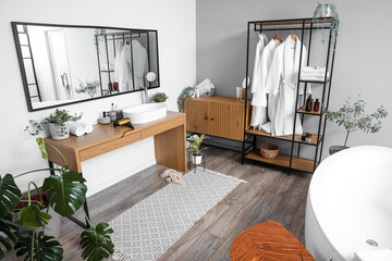 Interior of light bathroom with shelving unit, bathrobes and sink