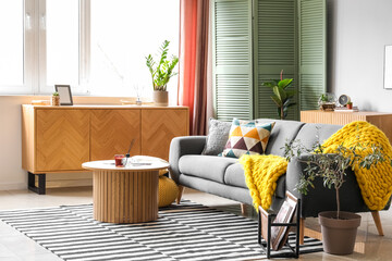Interior of bright living room with cozy grey sofa and coffee table