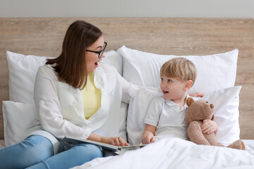 Nanny reading story to little boy in bedroom