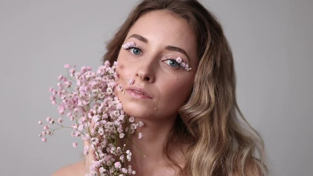 Portrait of a beautiful brunette woman with perfect skin and creative floral makeup look. Gypsophila eye makeup. The concept of cosmetic procedures, femininity, congratulations on women's day.