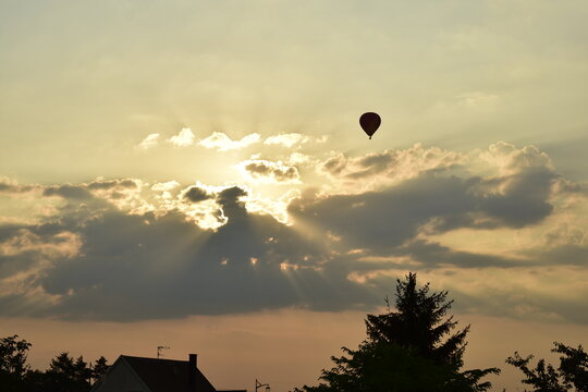 rayos de sol atravesando las nubes en un cielo nublado con un globo aerostático 