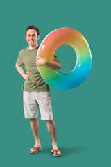 Young man with inflatable ring on green background