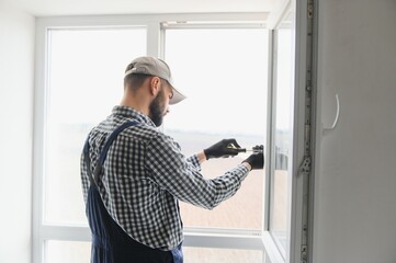 Fototapeta na wymiar Worker installing plastic window indoors